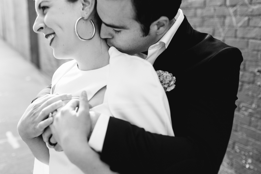 Groom kisses bride on the neck during their Brooklyn elopement in a classy black and white photo