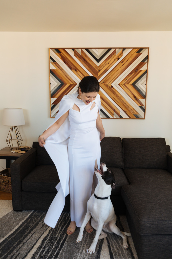 The bride stands with her rescue pup in her apartment in Brooklyn after her Brooklyn elopement at sunrise