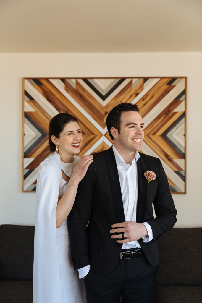 The bride and groom stand in their Brooklyn apartment together after their Brooklyn elopement at sunrise