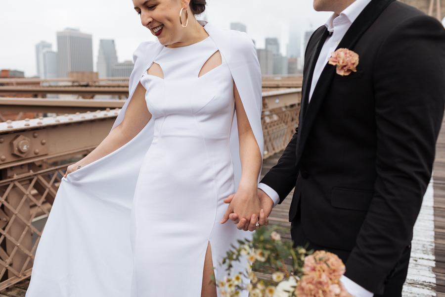 Bride shows groom her wedding dress cape and cut outs on her wedding dress during their Brooklyn elopement