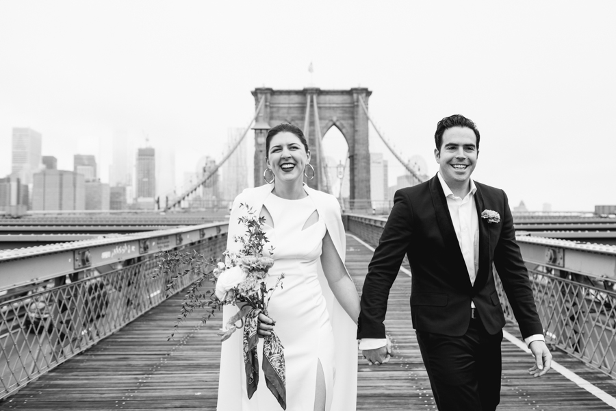 Bride and groom walk across the Brooklyn Bridge holding hands with each other after their Brooklyn elopement