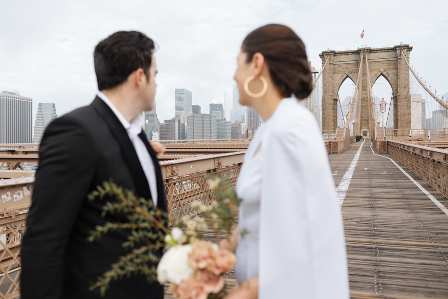 The Brooklyn Bridge behind the couple as they look out over New York City during their Brooklyn elopement