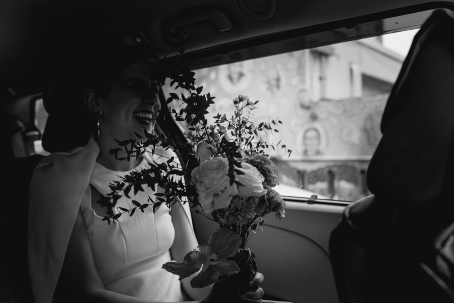 Bride holds her bouquet on her lap in the car on her way to her Brooklyn elopement