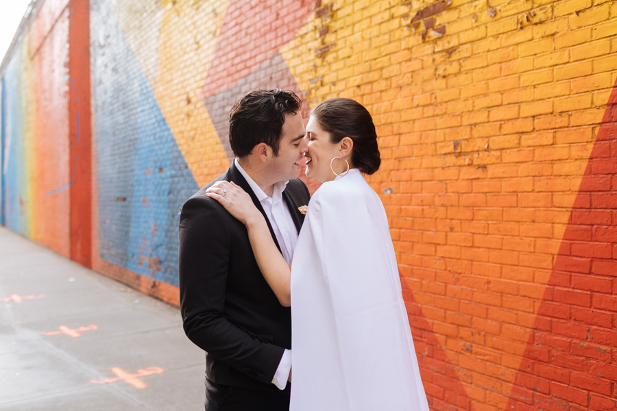The bride and groom kiss in front of a bright mural in Brooklyn during their Brooklyn elopement