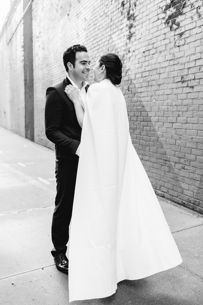 The bride and groom kiss in front of a bright mural in Brooklyn during their Brooklyn elopement but photo is in black and white