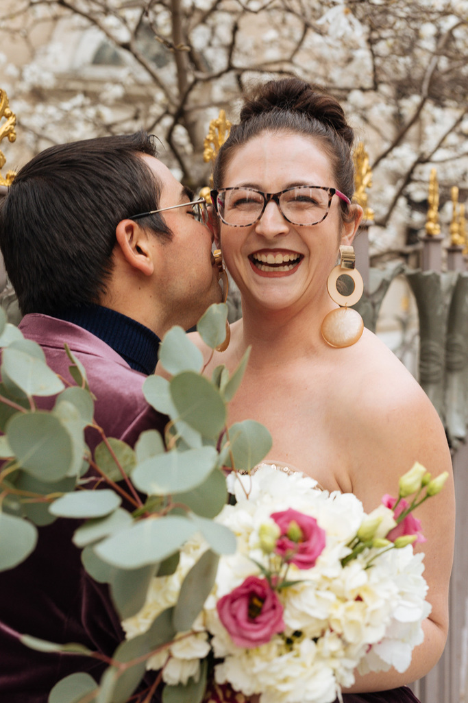 Groom whispers something in bride's ear during their East Village elopement in NYC