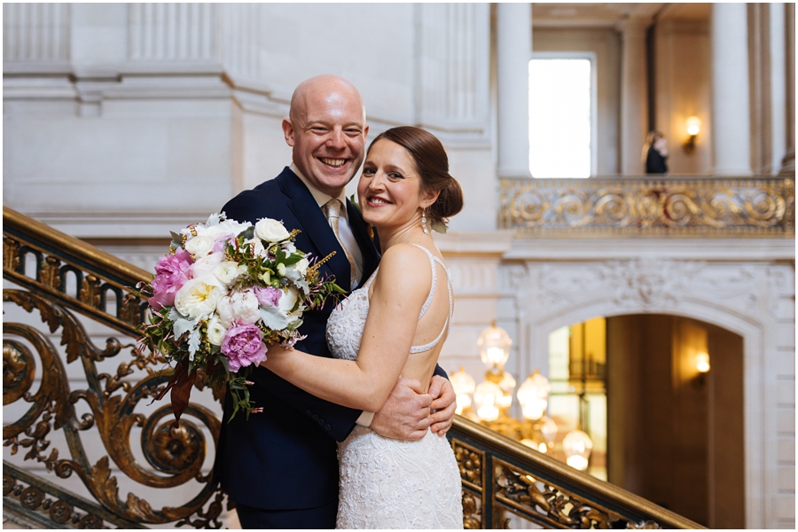 Couple smiles on the Grand Staircase during their San Francisco City Hall wedding in California