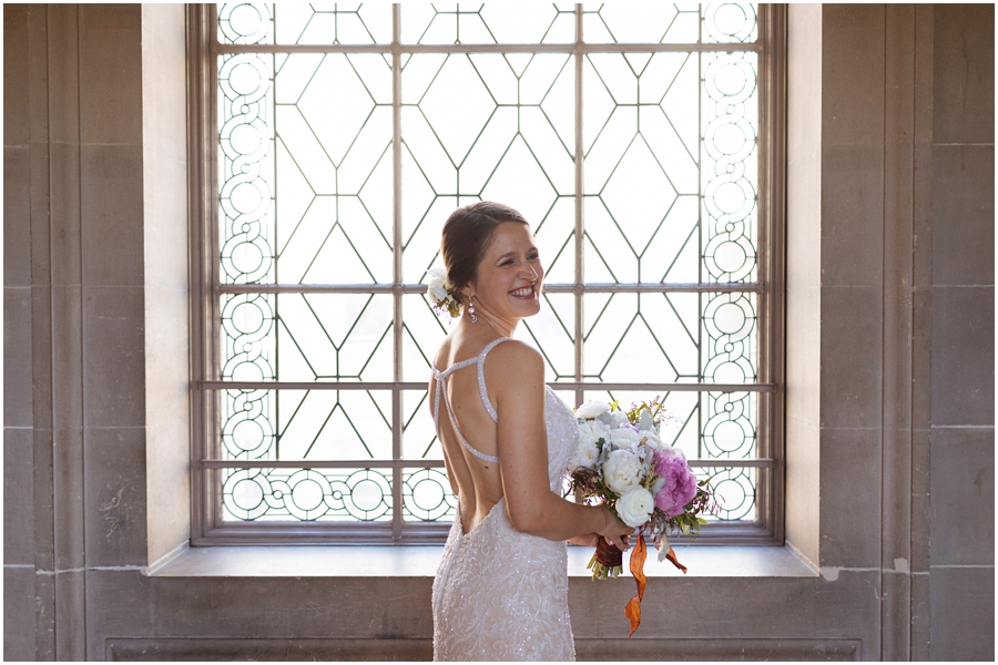 Bride laughs in front of an intricate and beautiful window