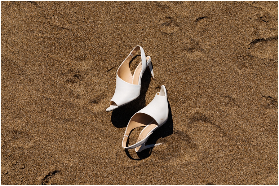 Bride's gorgeous white shoes sit in the sand during her San Francisco picnic wedding