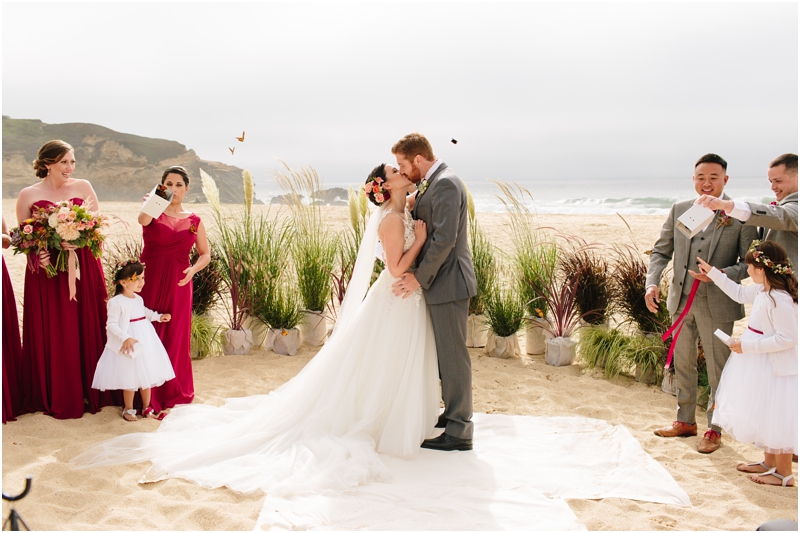 Bride and groom kiss during their wedding ceremony on the beach in Half Moon Bay outside of Half Moon Bay wedding venue La Costanera