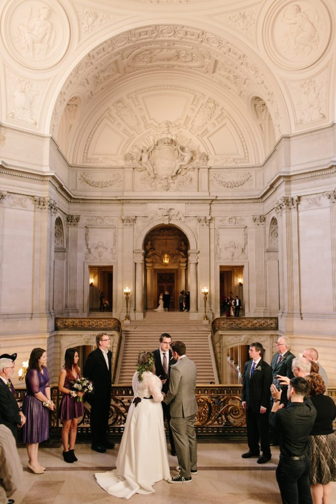 A marriage ceremony with guests standing in the Mayor's Balcony in San Francisco City Hall during a one hour ceremony